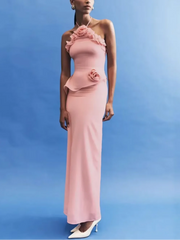 Woman wearing a pink evening gown with floral details against a blue background
