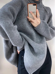 A person wearing a loose-fitting gray turtleneck pullover with double zippers at the front.