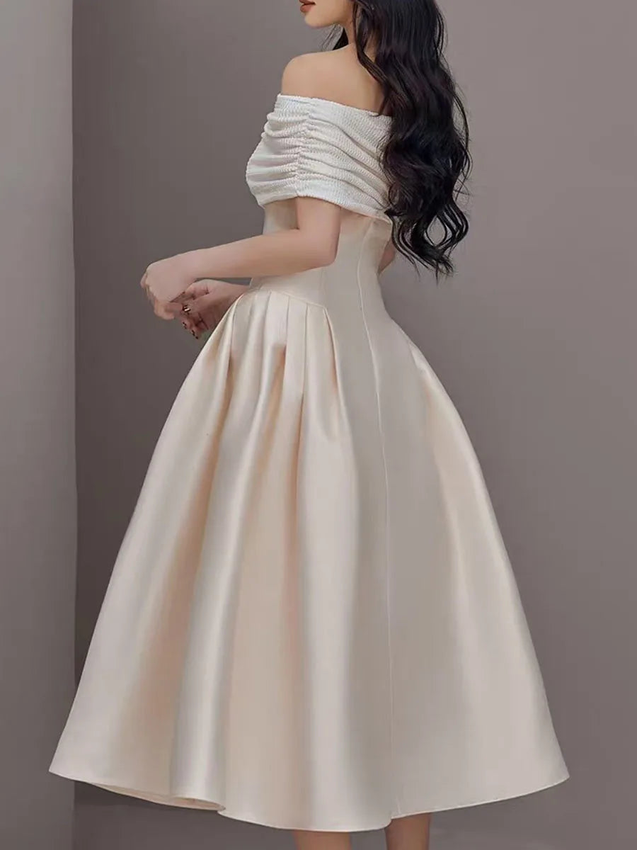 Woman wearing a white off-shoulder dress against a gray background