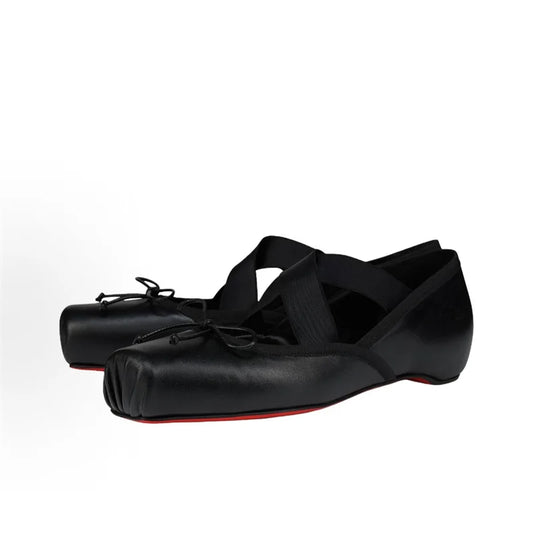 Black ballet shoes with red soles on a white background