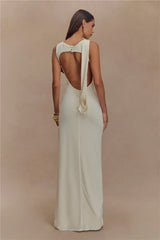 Woman wearing a white dress with a unique back design on a beige background