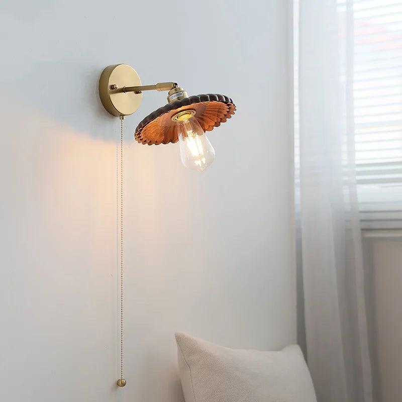 Wall-mounted lamp with wooden shade and gold fixture on a white wall.
