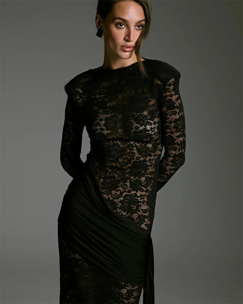 Woman wearing a black lace dress against a gray background