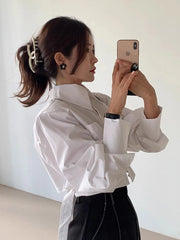 Person taking a mirror selfie wearing a white shirt and black pants.