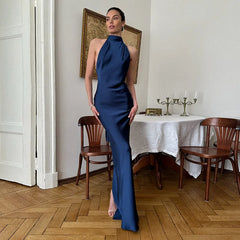Woman in a blue dress standing in a room with wooden flooring and a table.
