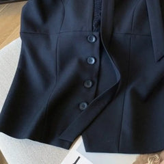Dark blue blazer with buttons on a light gray surface