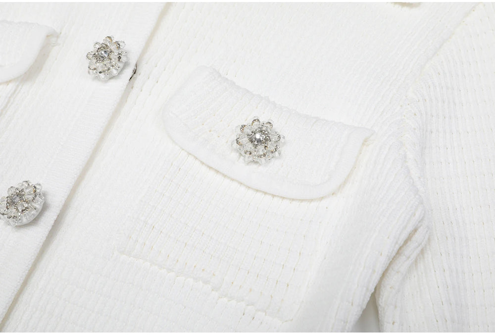 Close-up of white knit cardigan pocket and crystal button