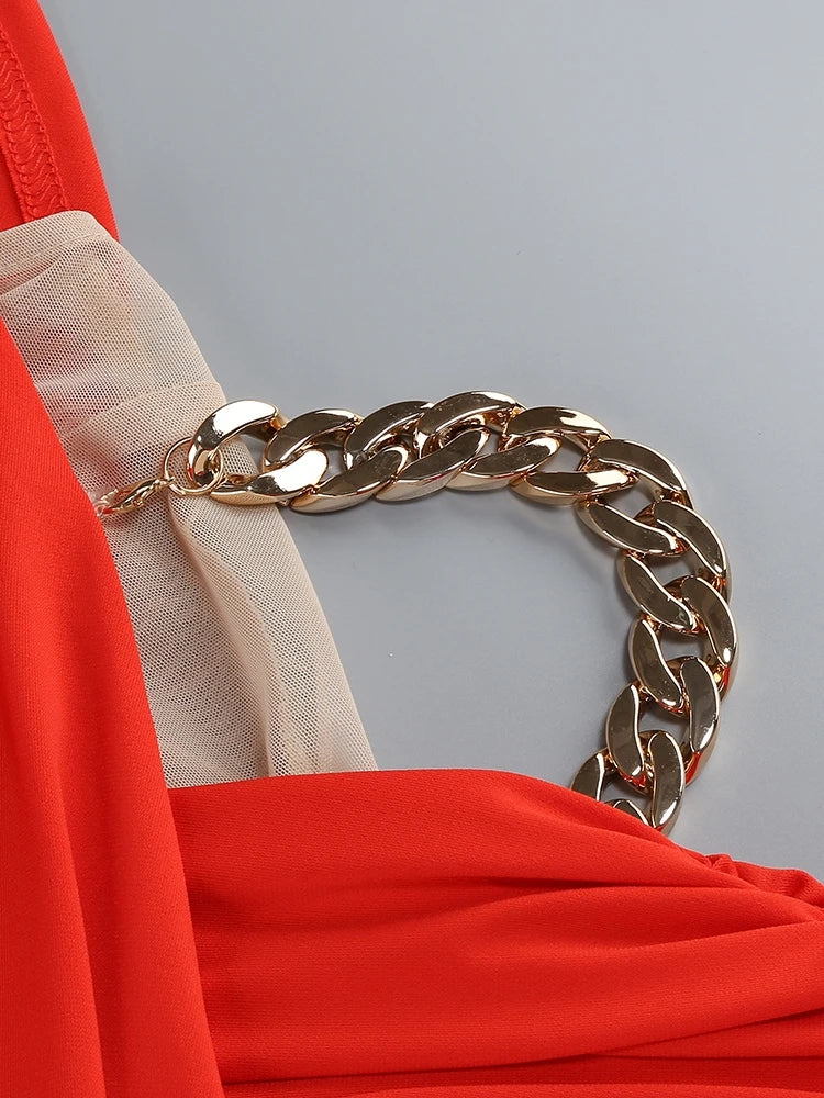 Gold chain belt on a person wearing a red outfit against a gray background