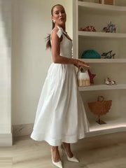 Woman in a white dress standing in a room with shelves displaying various items.