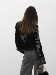 Back view of a cropped velvet jacket with silver embroidery.