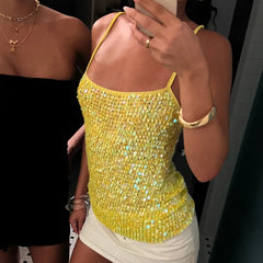 Person wearing a yellow sequin top with another person partially visible in the background.