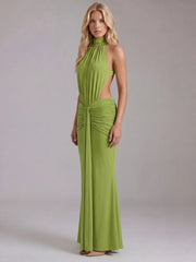 Side profile of a woman in a green halter neck draped maxi dress.