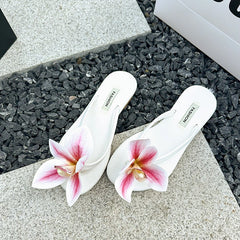 White sandals with pink floral designs on a gray surface