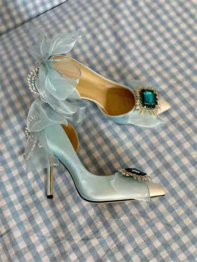 Teal high-heeled shoe with decorative elements on a checkered fabric background