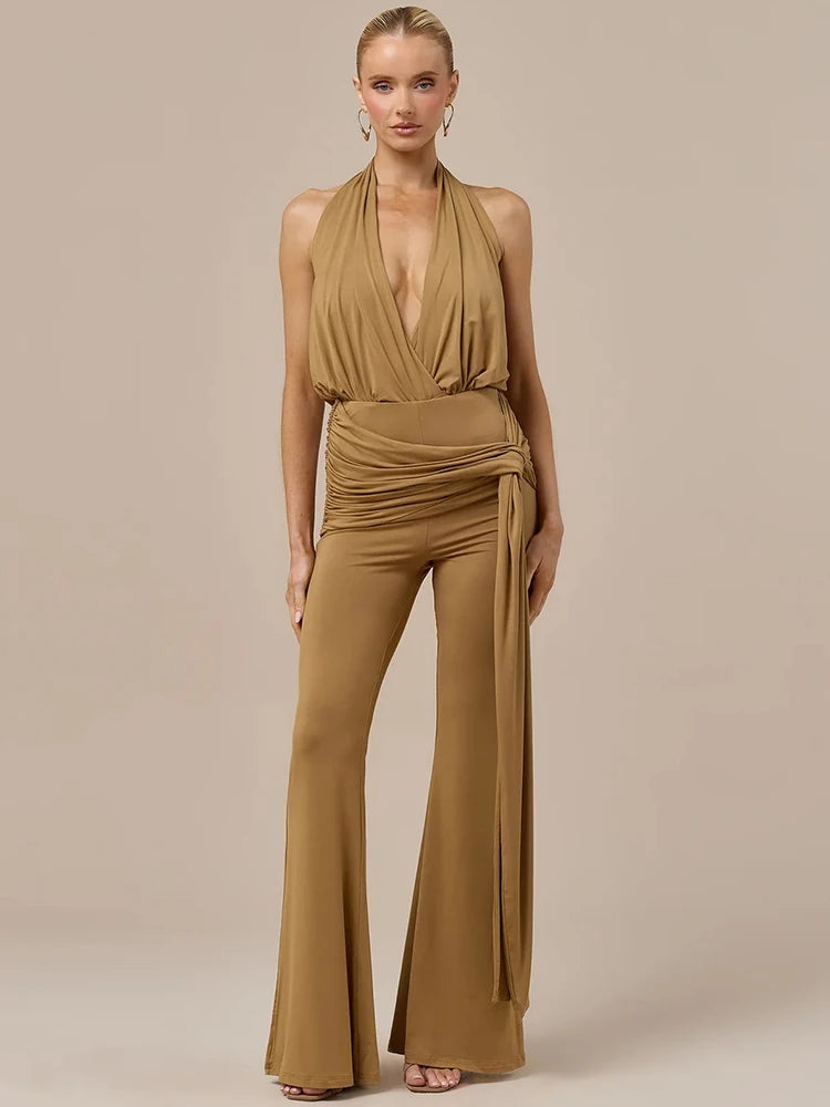 Woman wearing a tan draped halter top and matching wide leg pants set.