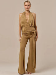 Woman wearing a tan draped halter top and matching wide leg pants set.