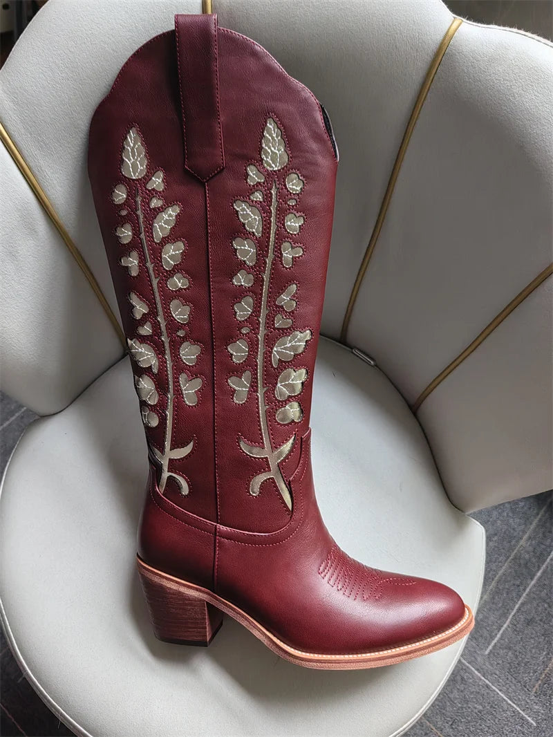 Maroon cowboy boot with white embroidery on a white chair