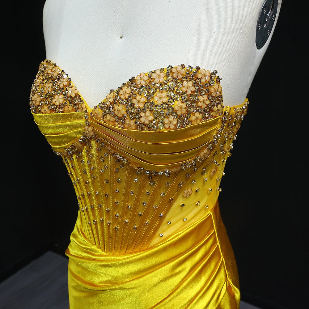Yellow evening gown with bead embellishments on a mannequin against a black background