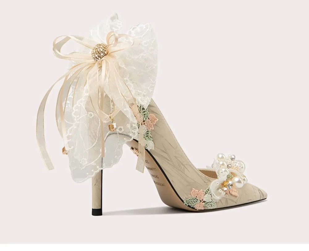 Delicate high-heeled shoes with floral and ribbon details on a light background