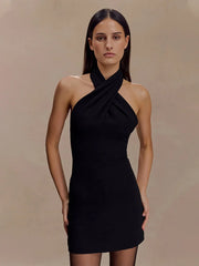 Woman wearing a black halter neck dress against a beige background