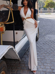 Woman in a white dress standing next to an old-fashioned vehicle on a cobblestone street.
