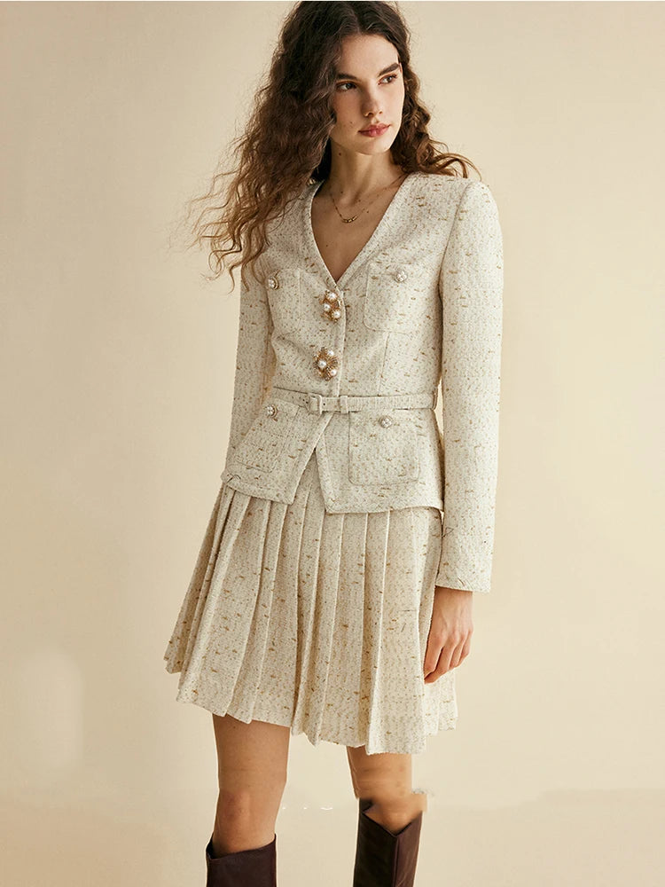 Woman wearing a light-colored suit with a pleated skirt on a beige background