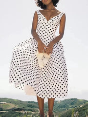 Woman wearing a white polka dot A-line mid dress outdoors with a scenic backdrop.