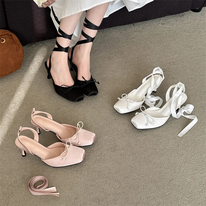 Black, pink, and white high-heeled shoes on a gray floor.