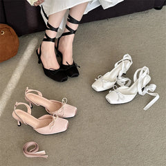 Black, pink, and white high-heeled shoes on a gray floor.
