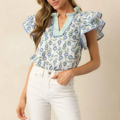 Woman wearing a floral blouse with ruffled sleeves on a beige background