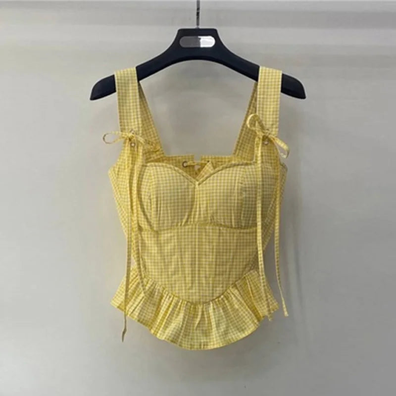 Yellow checkered top on a hanger against a gray background