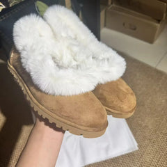 Close-up of fur trimmed suede ballet flats held by a hand