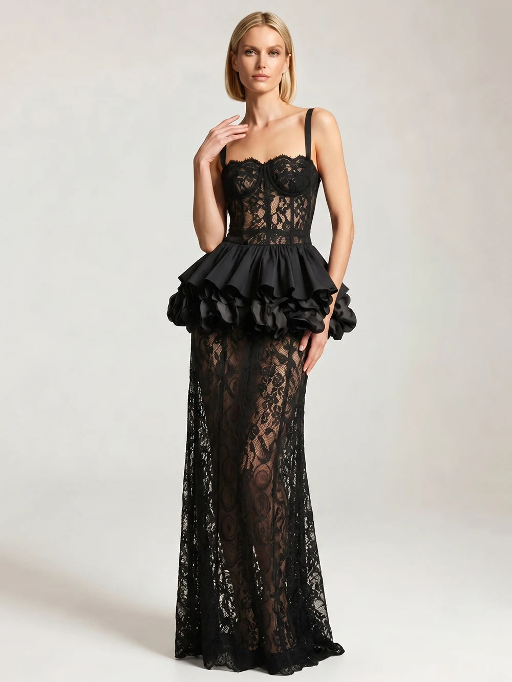 Model posing in a black lace corset top and sheath skirt set with spaghetti straps and a flounce detail.