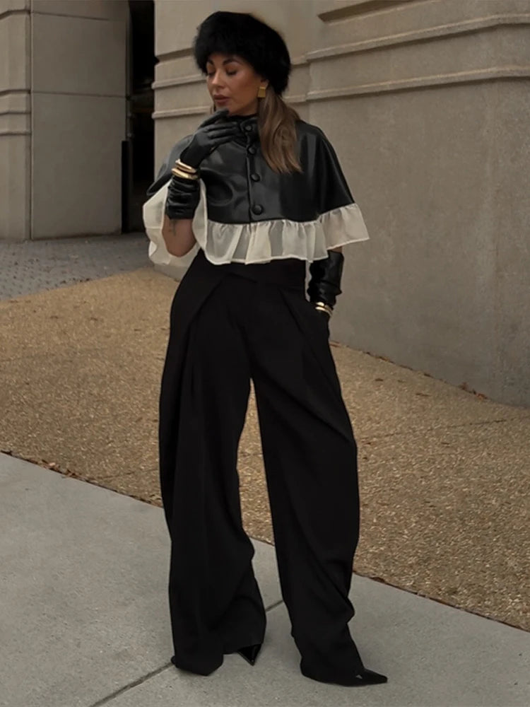 Person wearing a black and white outfit with wide-leg pants on a sidewalk.