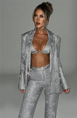 Woman wearing a silver sequin suit against a gray background