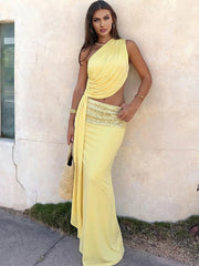 Woman in a yellow evening gown standing against a light-colored wall.