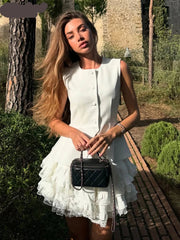 Woman in a white dress holding a black handbag in an outdoor setting
