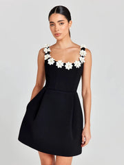 Black dress with white floral accents worn by a model on a plain background