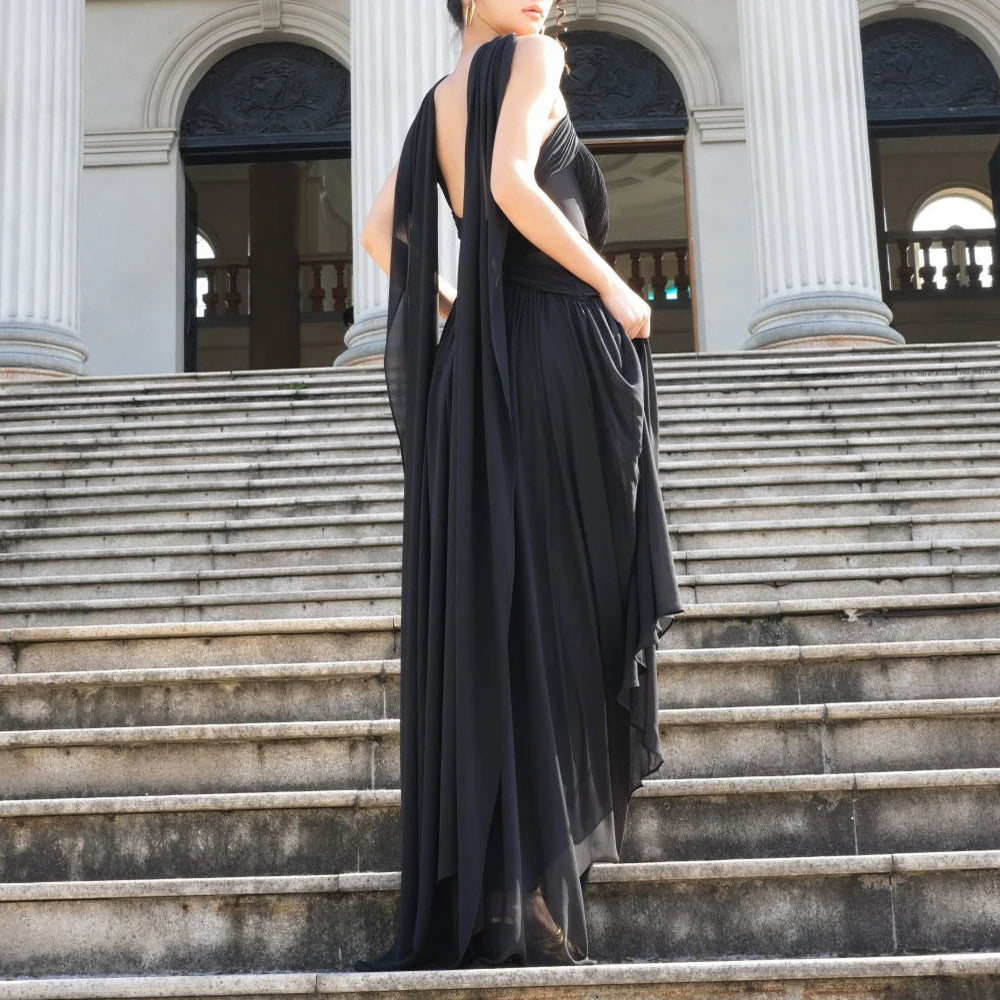 Woman in a black evening gown standing on stone steps with classical architecture in the background