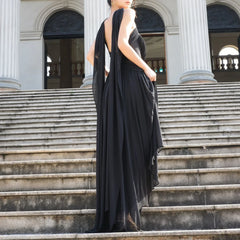 Woman in a black evening gown standing on stone steps with classical architecture in the background