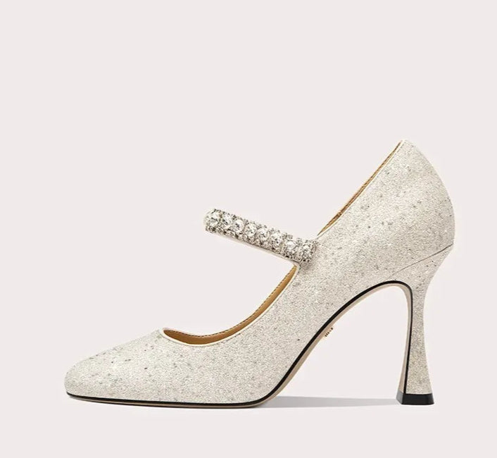 Sparkly high-heeled shoe with a decorative strap on a light gray background