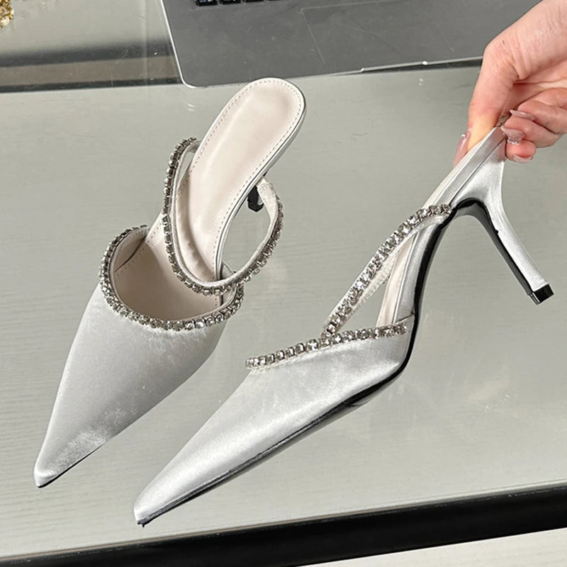 White heeled shoes with crystal embellishments on a reflective surface