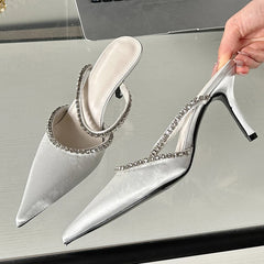 White heeled shoes with crystal embellishments on a reflective surface