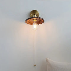Wall-mounted light fixture with a decorative shade on a plain wall.