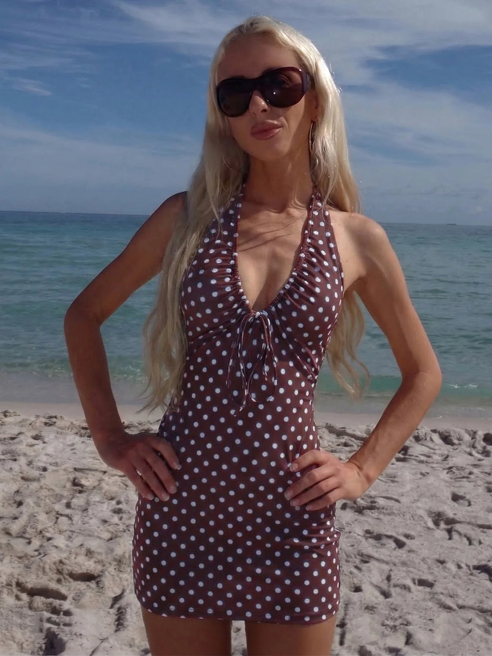 Woman in a polka dot dress and sunglasses on a beach