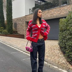 Woman wearing a red striped sweater and dark jeans standing on a street.
