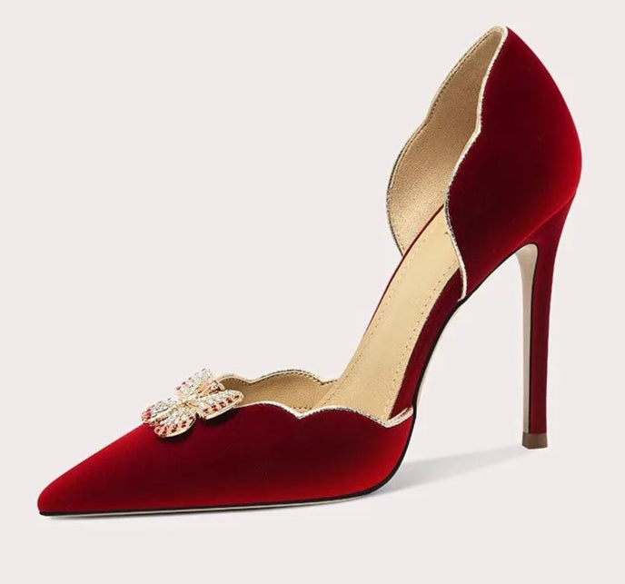 Red high-heeled shoe with gold embellishments on a white background