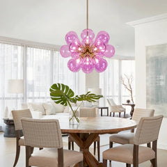 A cluster of Pink  glass bubble LED pendant lights hanging from a ceiling, illuminating a modern living room. Golden Atelier 2