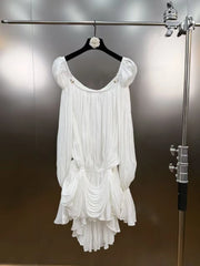 White dress hanging on a rack against a neutral background