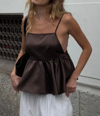 Woman wearing a brown peplum top and white skirt against a neutral background